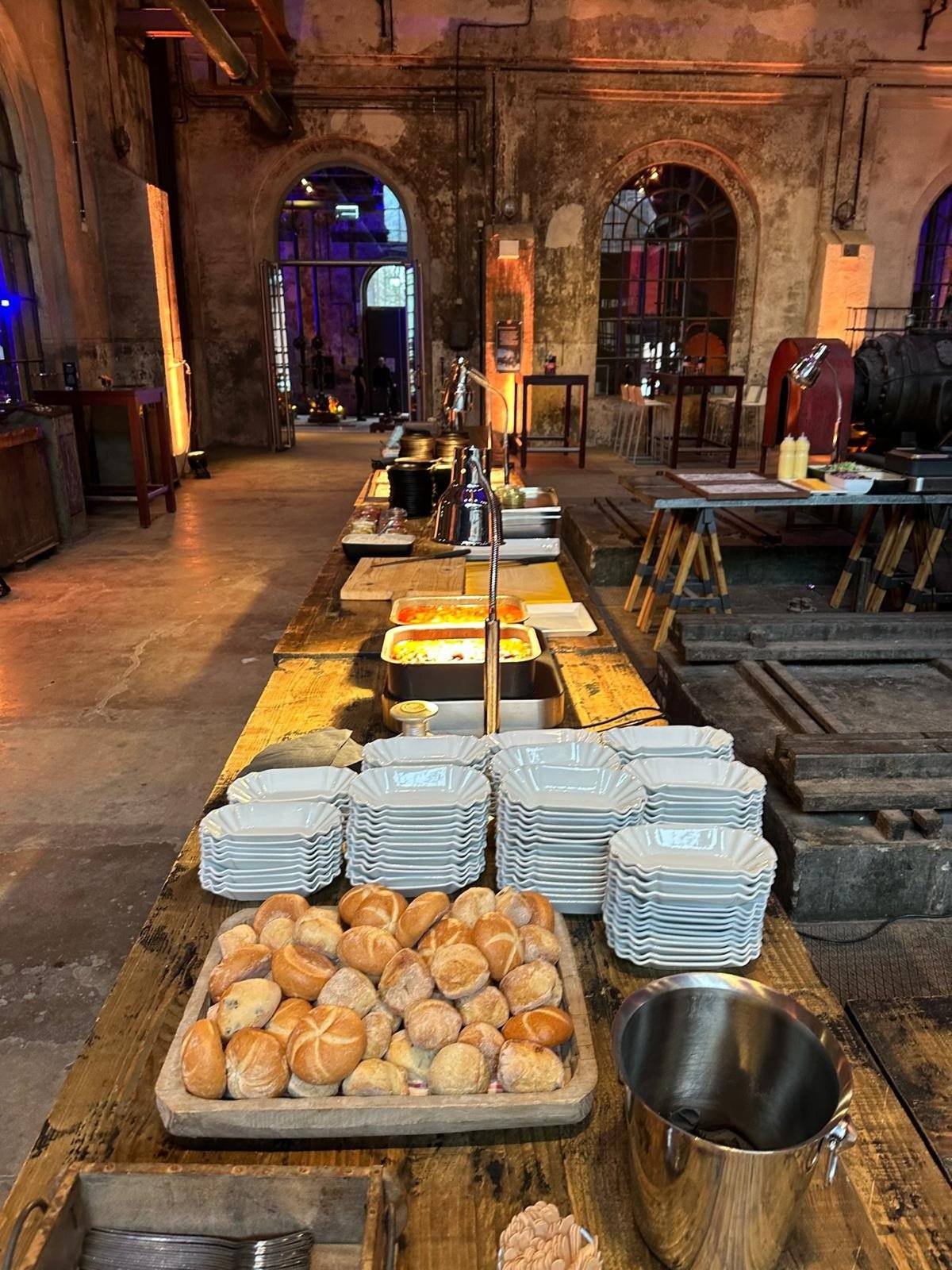 Buffet mit Brötchen und Warmhaltestationen in einer Eventhalle